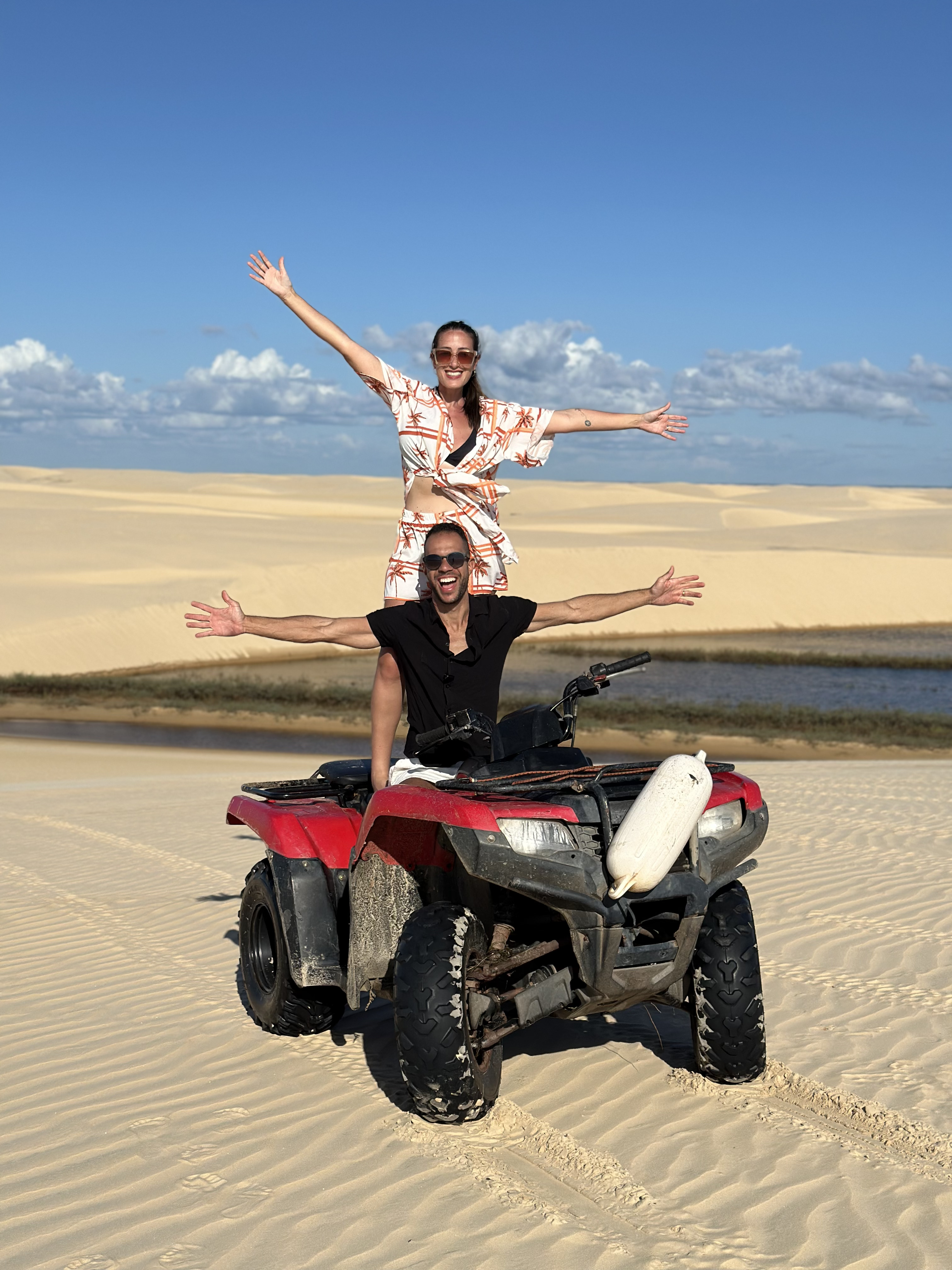 Casal comemorando em pé no quadriciclo nas dunas dos Lençóis Maranhenses