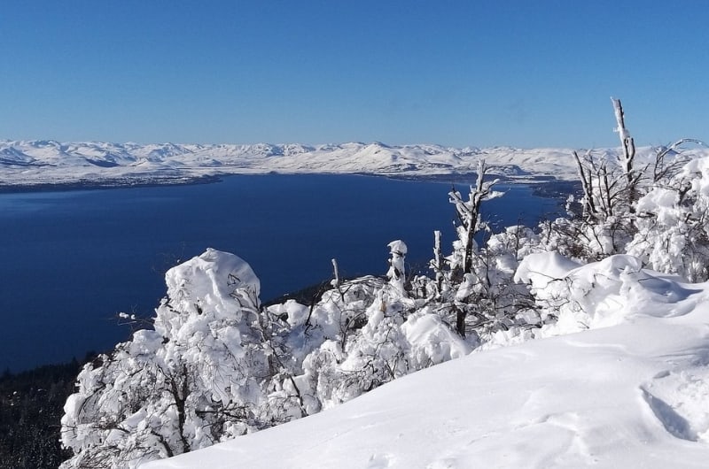 Árvores cobertas de neve e o Lago Nahuel Huapi vistos do Cerro Otto