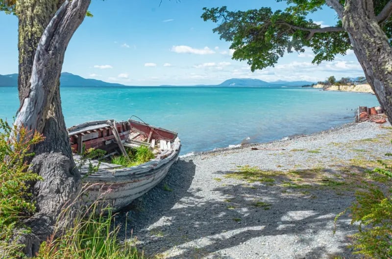 Barco antigo na margem de lago turquesa na região dos lagos de Ushuaia