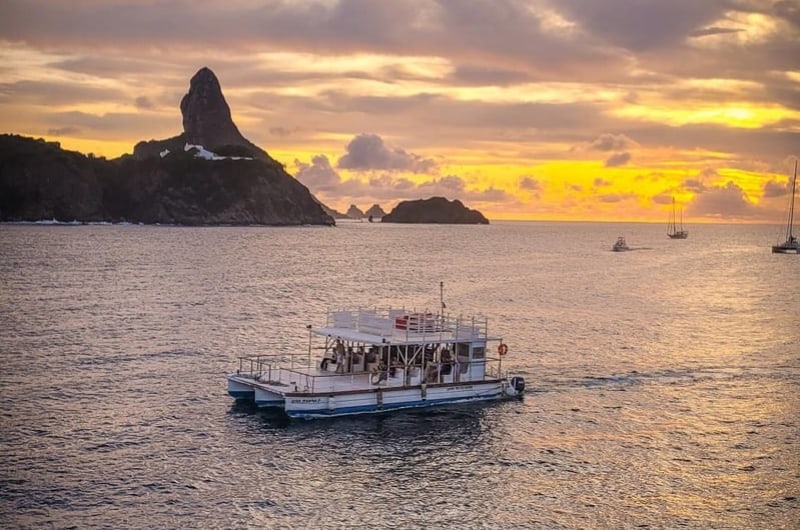 Barco ao pôr do sol diante dos morros de Fernando de Noronha