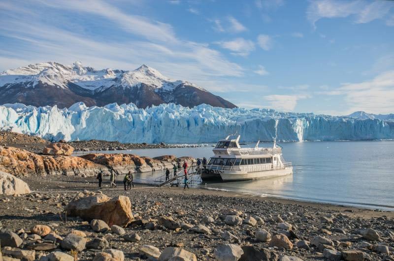 Barco do Safari Azul na margem de pedras com o glaciar ao fundo