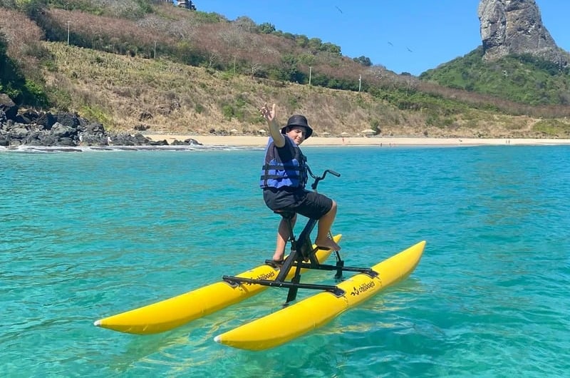 Bike aquática amarela no mar turquesa com o Morro do Pico