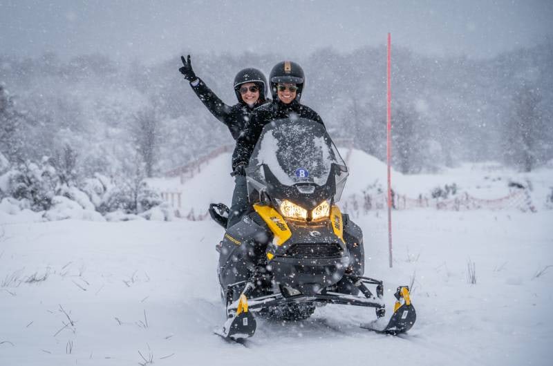 Casal acenando na moto de neve no Park Austral, em Ushuaia