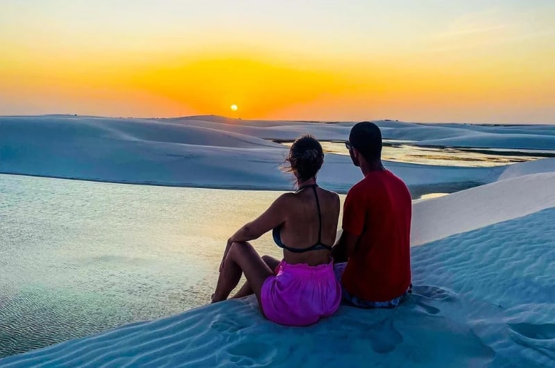 Casal sentado na duna ao pôr do sol em Santo Amaro do Maranhão
