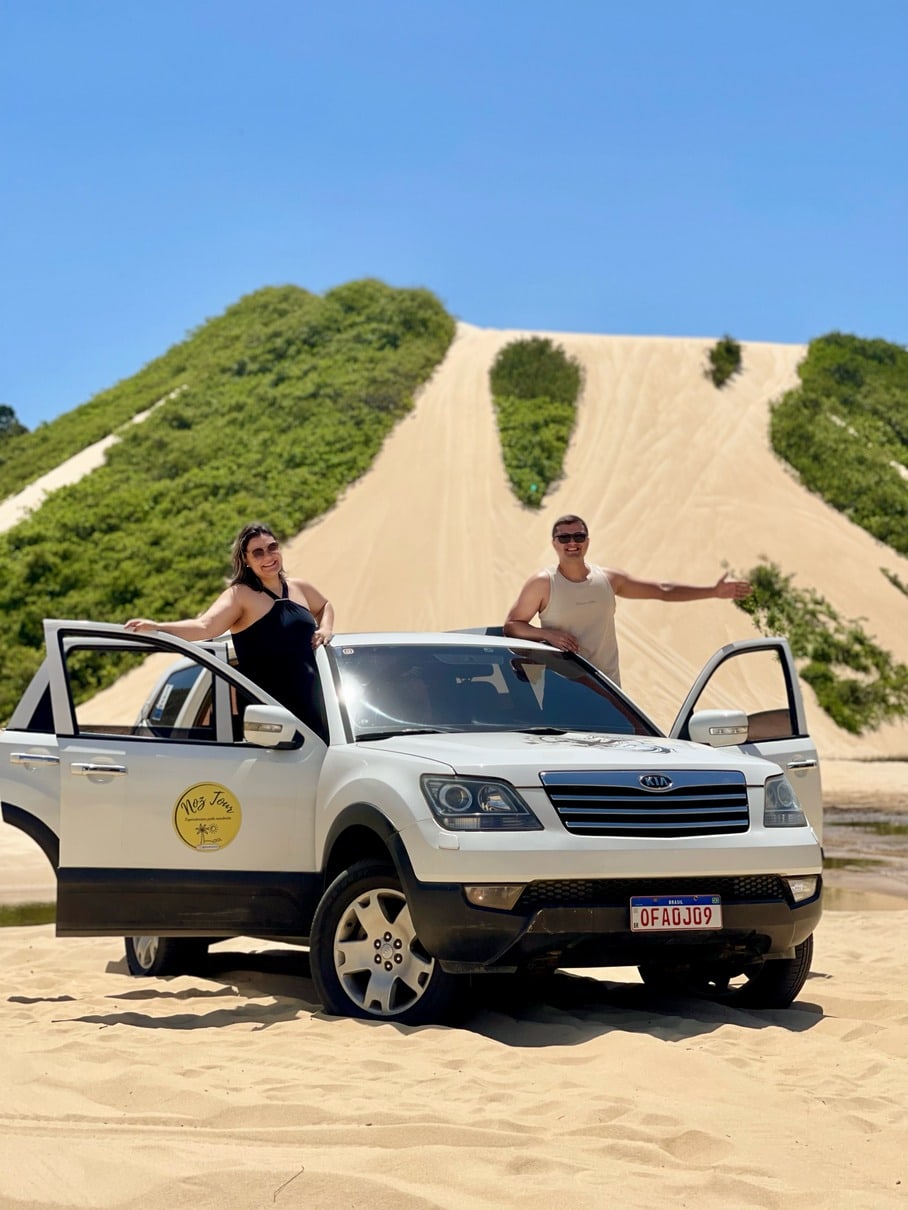 Casal ao lado do 4x4 no alto da duna no litoral sul potiguar