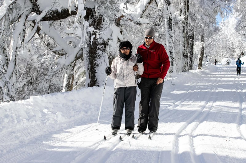 Casal com esquis em trilha nevada no batismo de esqui em Bariloche