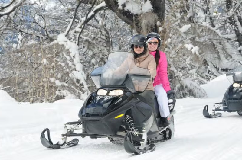 Casal em moto de neve no bosque do Cerro Catedral