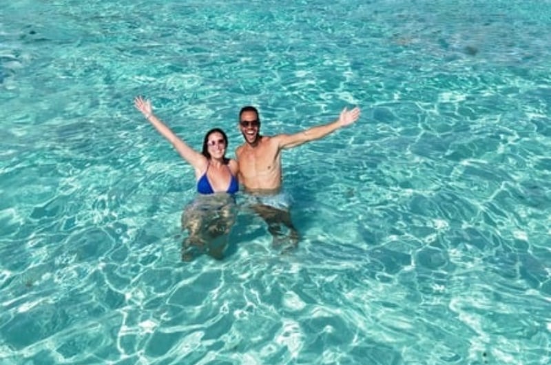 Casal na água cristalina durante o passeio de lancha