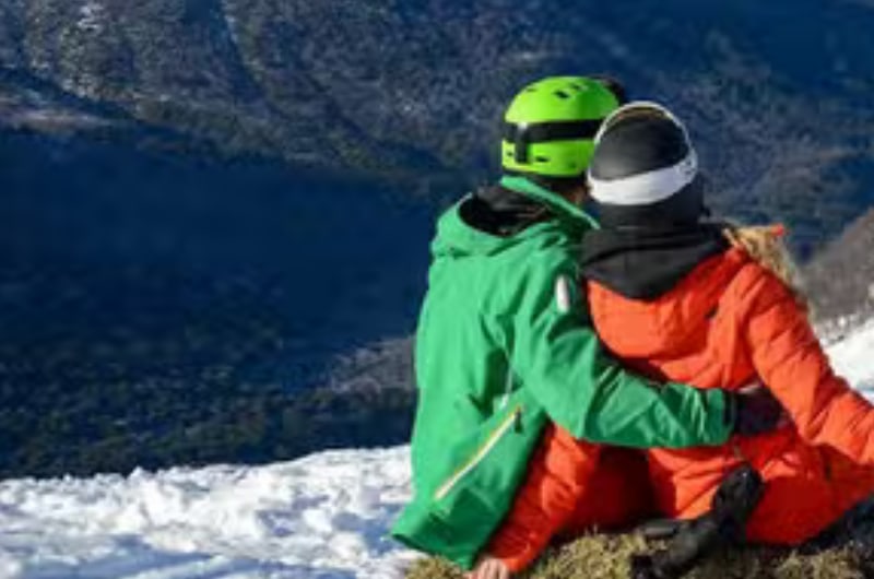 Casal na neve com vista para o lago no Cerro Bayo