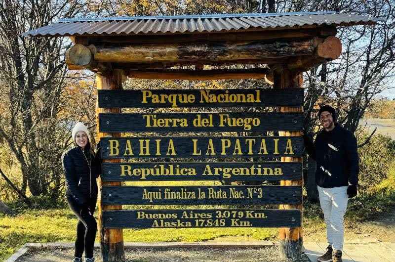 Casal na placa do fim da Ruta 3 na Bahía Lapataia, em Ushuaia