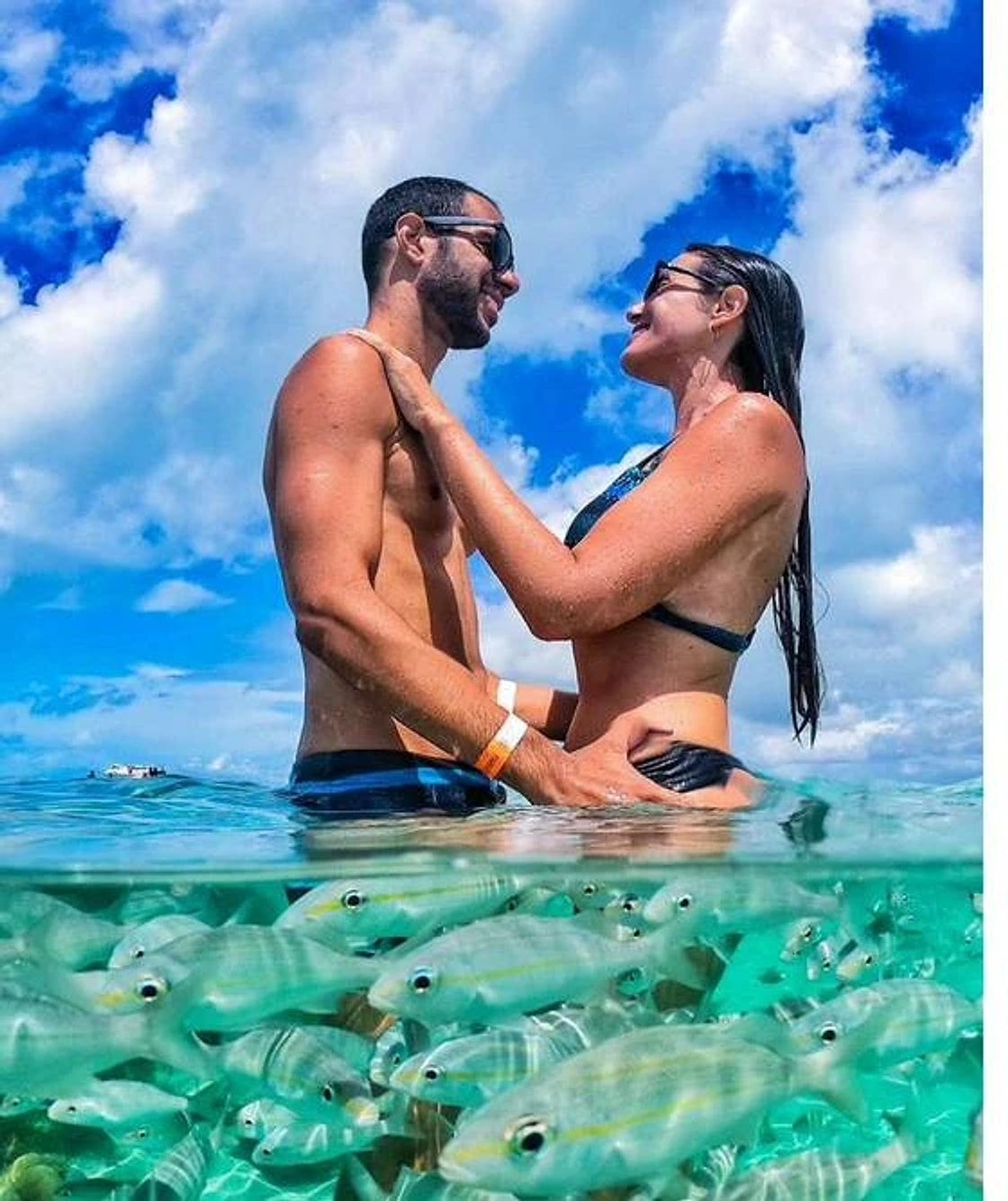 Casal nas piscinas naturais de Maracajaú, com peixes ao redor