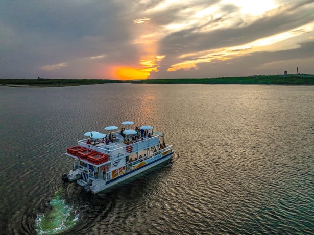 Catamarã do Auto do Potengi navegando no rio ao pôr do sol