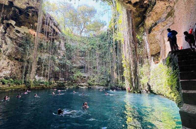 Cenote Ik Kil com raízes pendentes e pessoas nadando