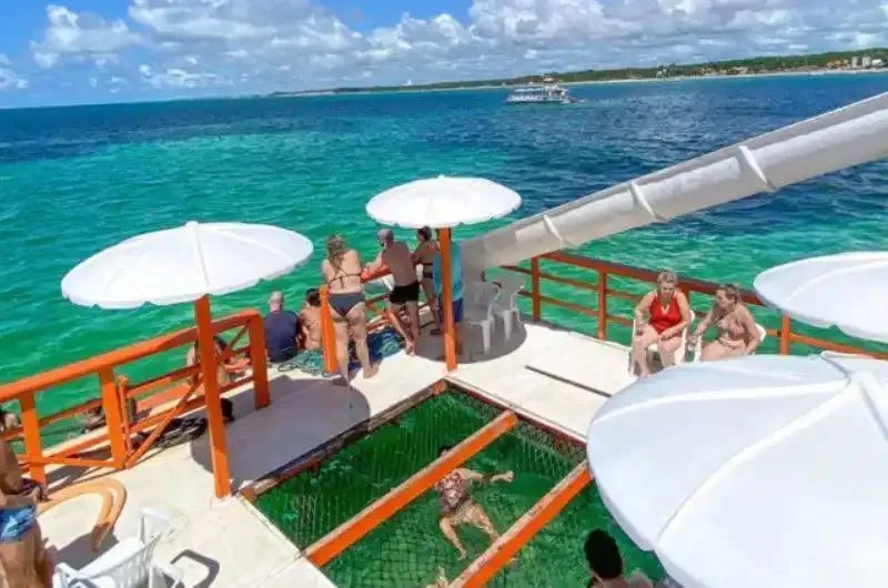Deck do barco com guarda-sóis e escorregador sobre as piscinas naturais