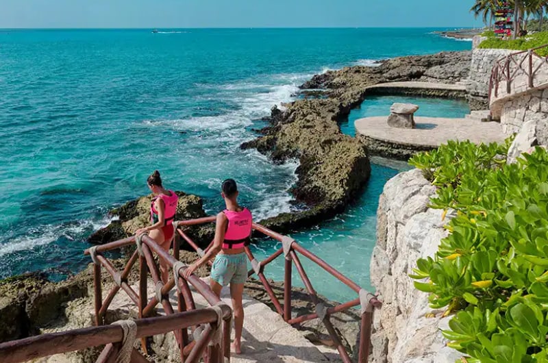 Enseada de água turquesa com passarela no Parque Xcaret