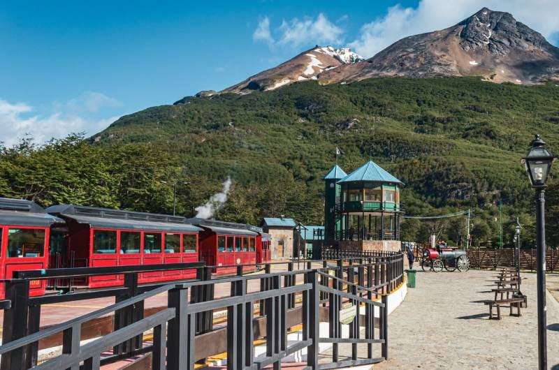 Estação do trem com vagões vermelhos e montanhas, no verão de Ushuaia