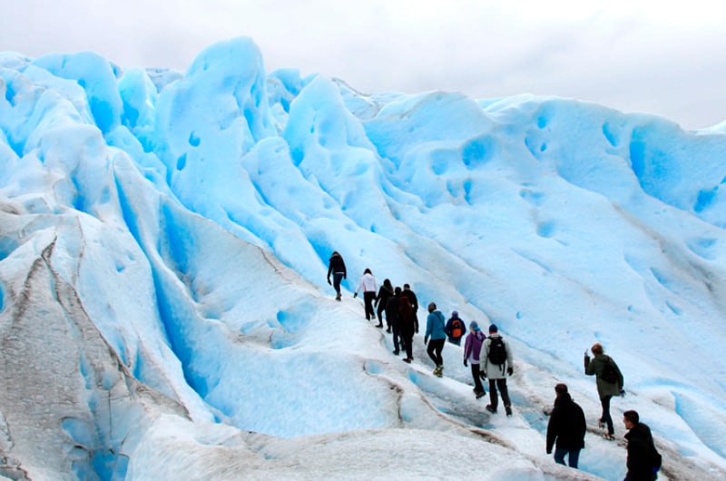 Fila de caminhantes entre paredes de gelo azul no Mini Trekking