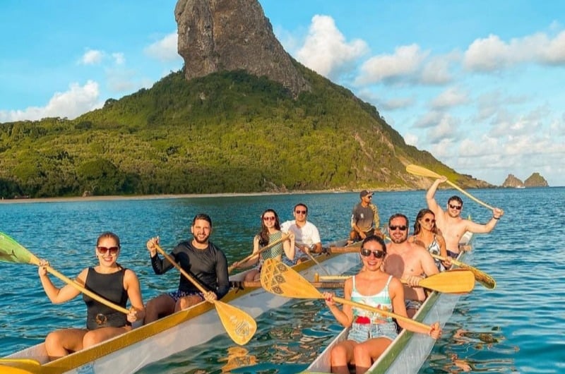 Grupo sorrindo na canoa havaiana no mar de Noronha