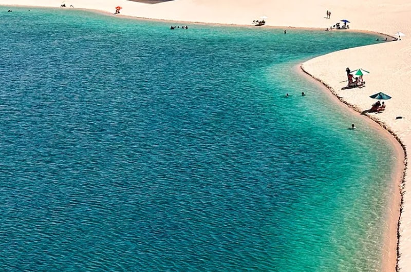 Lagoa turquesa com curva de areia branca nos Lençóis Maranhenses