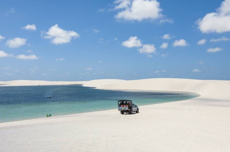 Lagoa com caminhonete 4x4 no alto da duna, em Santo Amaro