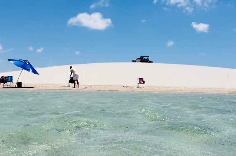 Lagoa com guarda-sol azul e 4x4 na duna em Ponta Verde, Santo Amaro