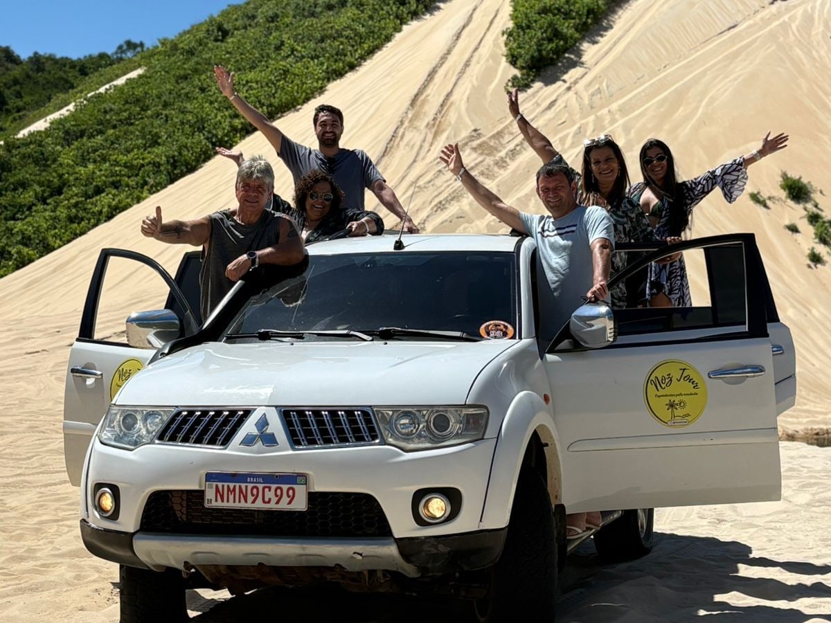 Grupo comemorando ao lado de uma caminhonete 4x4 da Noz Tour nas dunas de Natal