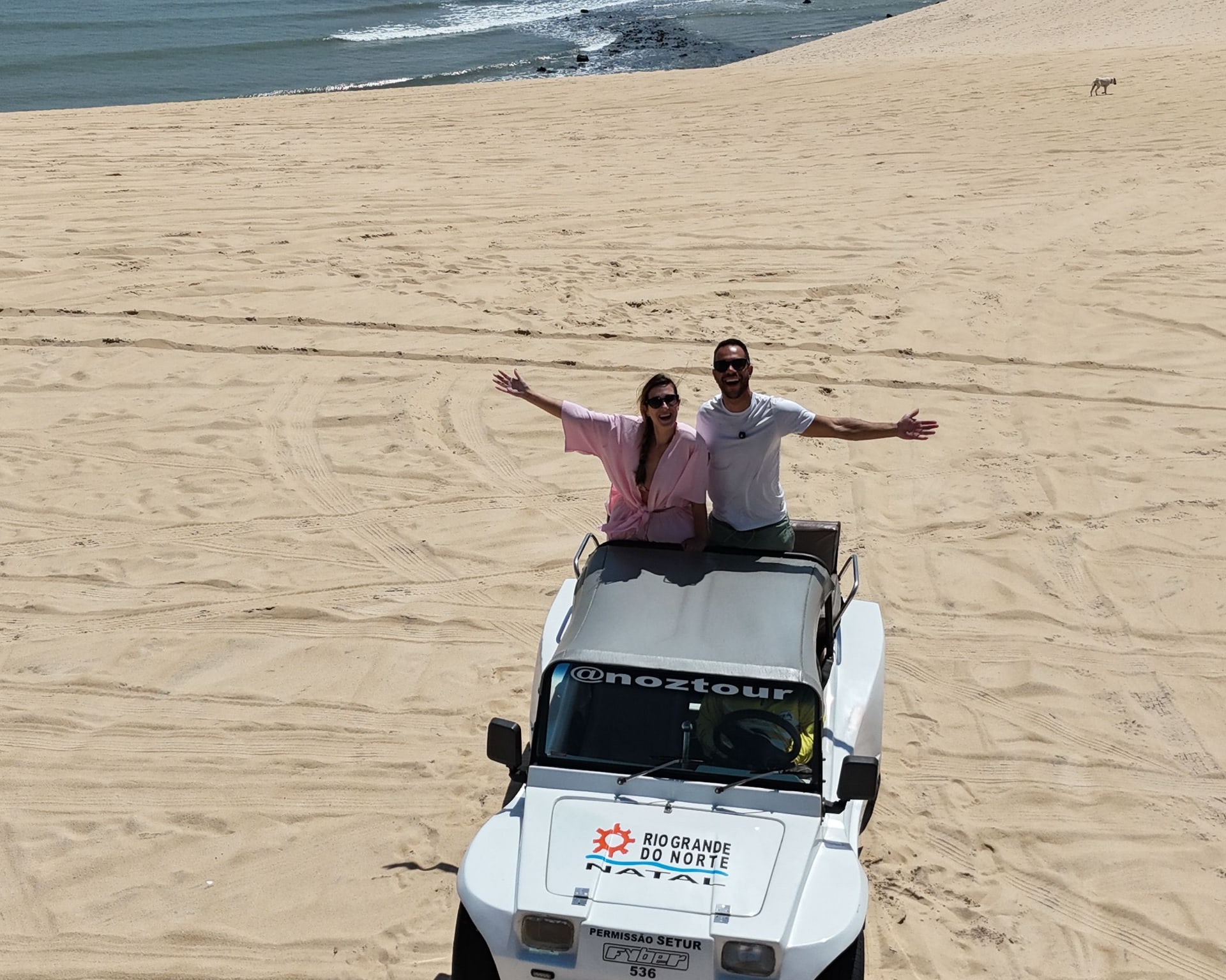 Casal em pé no buggy da Noz Tour nas dunas do litoral norte de Natal, com o mar ao fundo