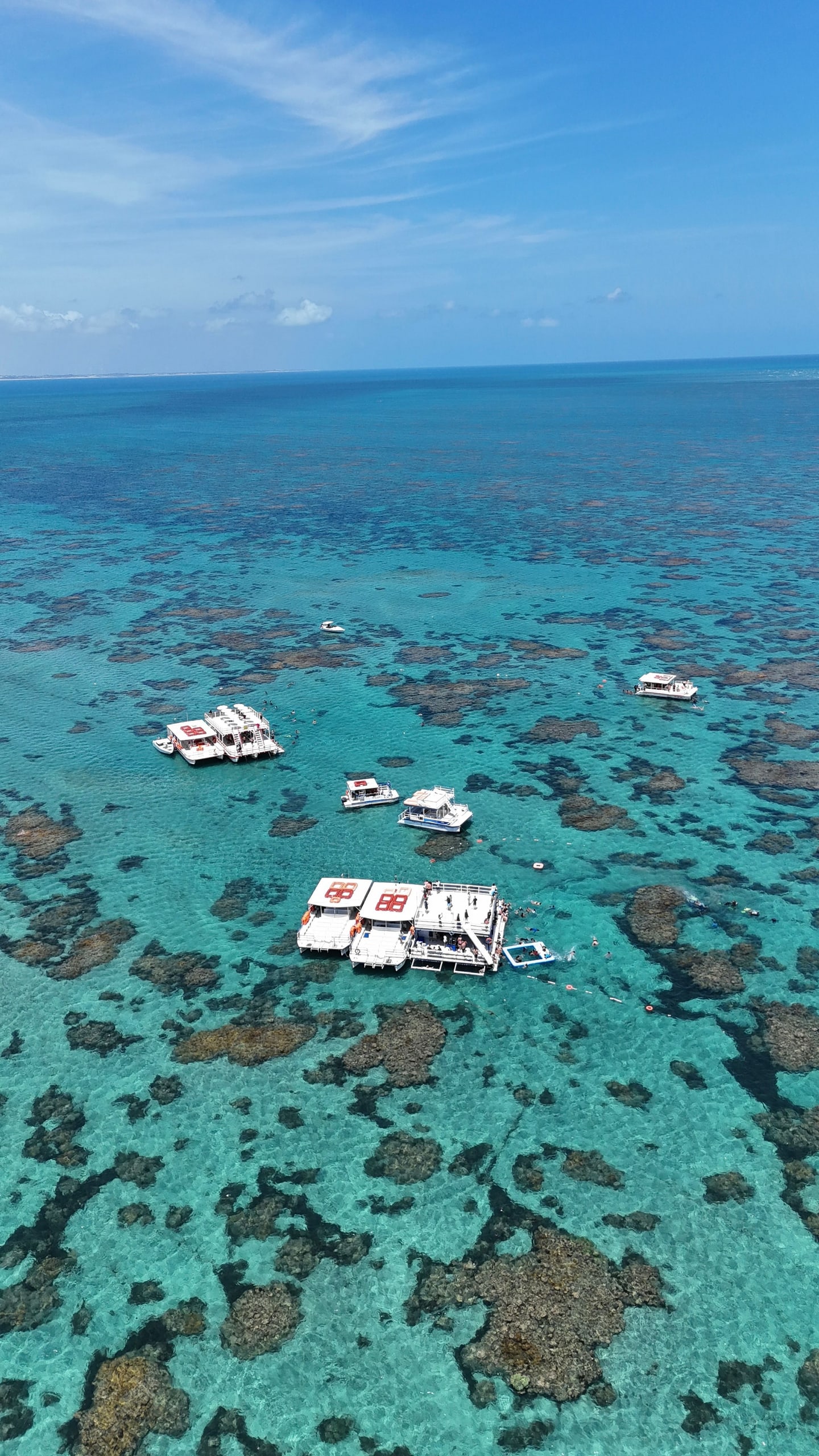 Vista aérea dos catamarãs parados sobre os recifes nas piscinas naturais de Maracajaú