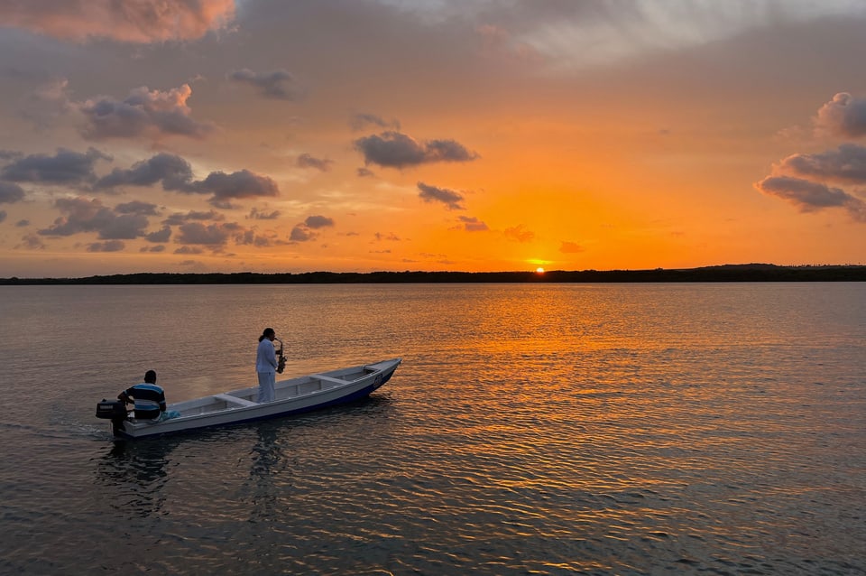 Pôr do sol no rio com barco na Praia do Jacaré, em João Pessoa
