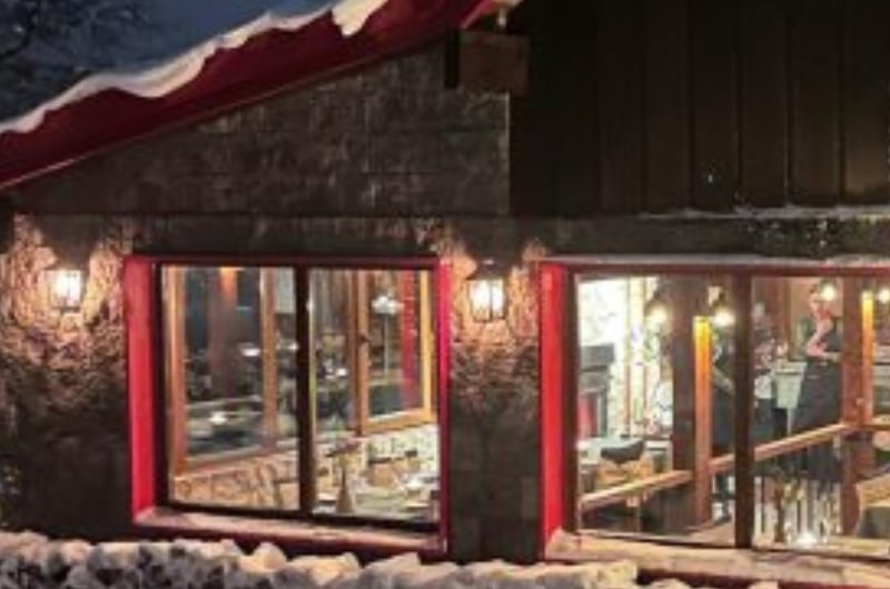 Refúgio de montanha iluminado na neve durante a Noite Nórdica