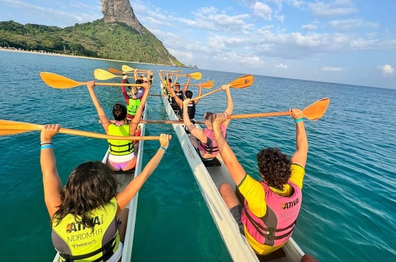 Remadores erguendo os remos na canoa havaiana em Noronha
