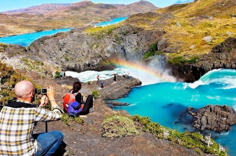 Viajante fotografando o Salto Grande com arco-íris, em Torres del Paine