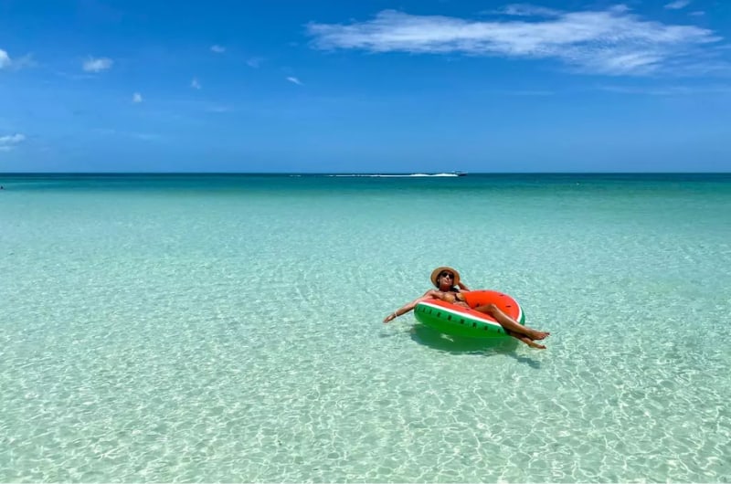 Viajante numa boia no mar raso de Holbox