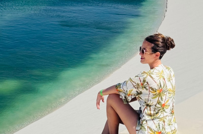 Viajante sentada na duna junto à lagoa nos Lençóis Maranhenses