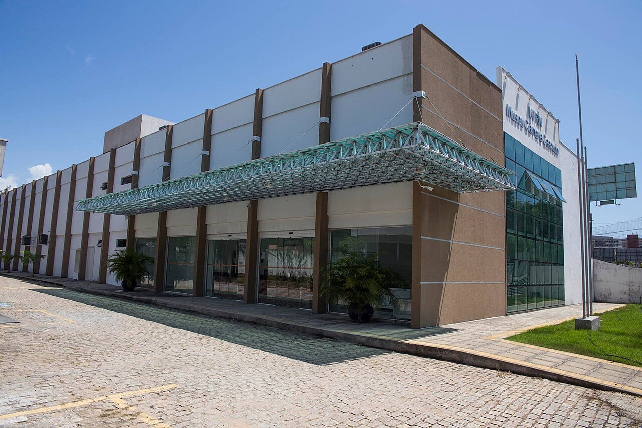 Fachada do prédio de exposições do Museu Câmara Cascudo, com marquise de vidro e plantas na entrada, no Tirol, em Natal