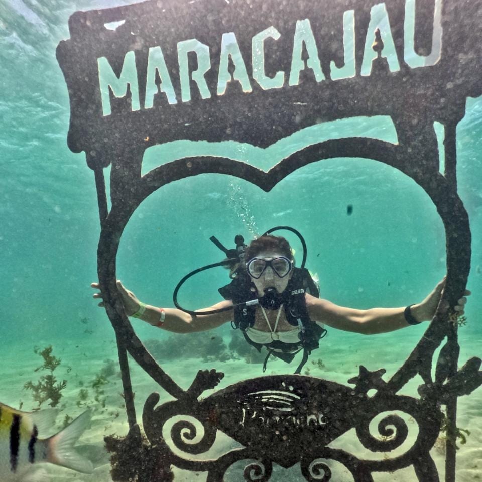 Mergulhador com cilindro dentro da moldura de coração com o nome Maracajaú, no fundo do mar