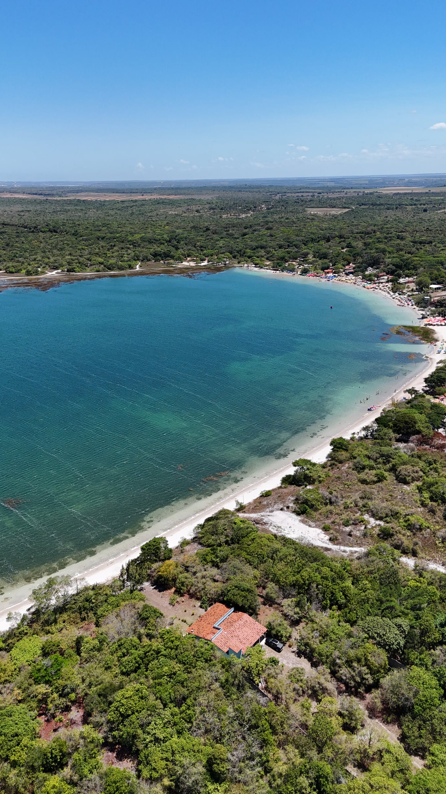 Vista aérea da Lagoa do Carcará, de água azul e margem de areia clara, cercada de mata em Nísia Floresta
